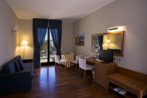 a living room with a desk with a television and a table with chairs at Hotel Tiziano in Trapani