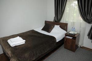 um quarto com uma cama e uma mesa de cabeceira com toalhas em Hotel Brick House em Samarkand