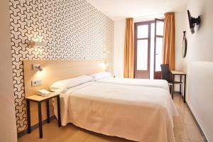 a hotel room with a large bed and a window at Atenas Granada in Granada