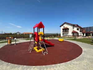 um parque infantil com um escorrega vermelho e amarelo em Pensiunea Coralia em Murighiol