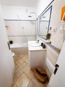 a bathroom with a sink and a tub and a mirror at Mira Vila Studio - Duna Parque Group in Vila Nova de Milfontes