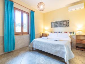 een slaapkamer met een bed met blauwe gordijnen en een raam bij Casa Ida - Wonderful Vacation in Putzu Idu