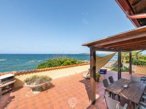 un patio con tavolo, sedie e vista sull'oceano di Casa Ida - Wonderful Vacation a Putzu Idu
