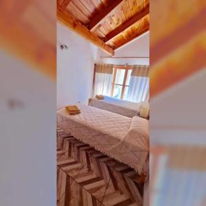 um quarto com uma cama num quarto com tectos em madeira em Alberdi Tempo em Esquel