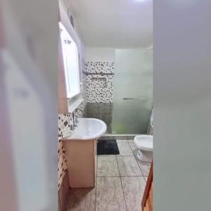 uma casa de banho com um lavatório e um WC em Alberdi Tempo em Esquel