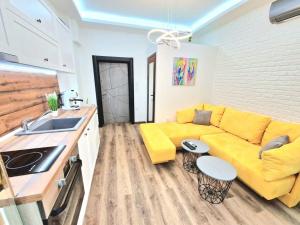 a living room with a yellow couch and a kitchen at The Little Prince studio in Varna City