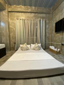 a large white bed in a room with curtains at Hai Inn in Dumaguete