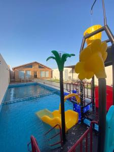 una grande piscina con scivolo e parco giochi di أكواخ وشاليهات باشن الريفية a Khalij Salman