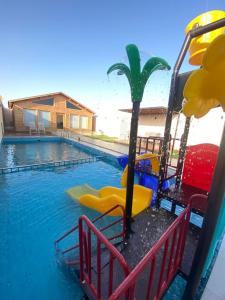 a swimming pool with a water slide and a palm tree at أكواخ وشاليهات باشن الريفية in Khalij Salman