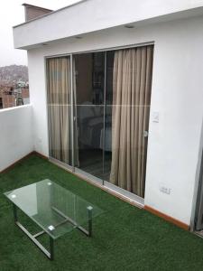 balcón con mesa de cristal y césped verde en Hermoso Duplex en Chorrillos, en Lima