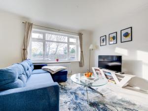 a living room with a blue couch and a glass table at Pass the Keys Bright Spacious Home Away From Home With Parking in Abbey Wood