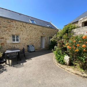 a brick house with a table and a garden with flowers at Penty á Plogoff-Pointe du Raz in Plogoff