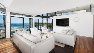 a living room with white furniture and glass windows at Sails on the Beachfront - Exclusive Seaside Home in Anna Bay