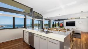 an open kitchen and living room with a view of the ocean at Sails on the Beachfront - Exclusive Seaside Home in Anna Bay