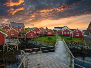 een groep rode huizen op het water met een dok bij Reine Rorbuer - by Classic Norway Hotels in Reine