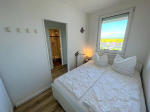 een slaapkamer met een groot wit bed en een raam bij Ferienpark Sierksdorf App 782 - Strandlage in Sierksdorf