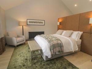 a bedroom with a large bed and a chair at Garden House in Amlwch