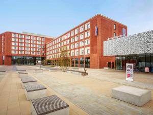 a courtyard with benches in front of a building at Novotel Cambridge North in Cambridge