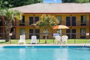 a hotel with a swimming pool with chairs and an umbrella at Knights Inn Aiken in Aiken