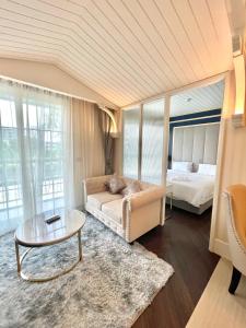 a bedroom with a bed and a table and a couch at Grand Florida Beachfront Resort Jomtien Pattaya in Na Jomtien