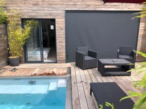 un patio con piscina, 2 sillas y una mesa en Loft privatisé avec spa XXL et piscine chauffée en Bruz