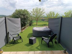 een achtertuin met twee stoelen en een bed op het gras bij L'Eden in Tonneins