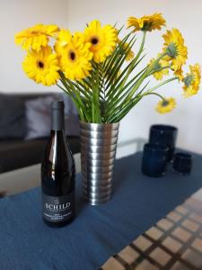 een fles wijn en een vaas met bloemen op een tafel bij Casa Kühn in Hackenheim