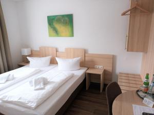 a large white bed in a room with a table at Hotel Zum Prinzen Sinsheim in Sinsheim