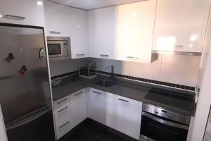 een keuken met witte kasten, een wastafel en een koelkast bij Apartamento Playa Foz in Foz