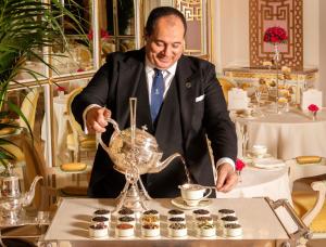 a man in a suit preparing cupcakes in a restaurant at The Ritz London in London