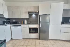 una cocina con electrodomésticos blancos y armarios blancos en Coquet studio vue mer pour 4 personnes au Port de Valras-Plage, en Valras-Plage