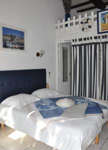 a bedroom with a large bed with a blue headboard at Hôtel Les Mimosas in Bormes-les-Mimosas