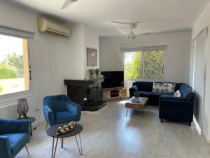 a living room with blue chairs and a couch and a tv at Coral Bay new furnished private villa with pool in Peyia