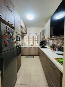 cocina con armarios de madera y nevera de acero inoxidable en The Haven Suite en Bentong