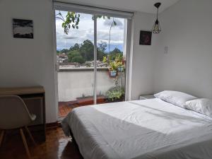 a bedroom with a bed and a large window at Habitación en COLIVING penthouse centro histórico in Popayan
