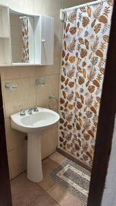 a bathroom with a sink and a shower curtain at Alquiler por día. in Firmat