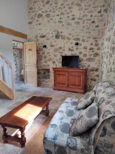 a living room with a couch and a tv at La Grange de Sabatas in Chomérac