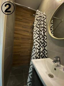 een badkamer met een wastafel en een douche met een spiegel bij Studio Aparment in Charkov