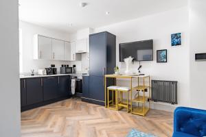 a kitchen with blue cabinets and a table and chairs at Livestay-Modern Apartments in Romford near Elizabeth Line in Romford