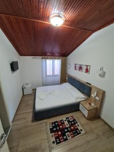 a bedroom with a bed and a wooden ceiling at Hotel Darda in Kamëz