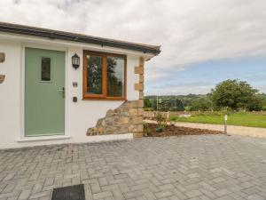 a white house with a green door and a patio at Bumble Bee Retreat in Axminster