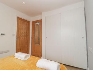 a bedroom with a bed with white walls and a wooden door at Bumble Bee Retreat in Axminster