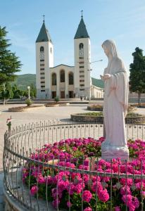 a statue of a woman standing next to a bed of flowers at Pansion Raspudić in Međugorje