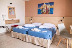 una camera da letto con un grande letto con lenzuola blu e cuscini bianchi di Achilleas Hotel Apartments a Città di Kos