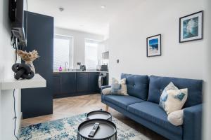 ein Wohnzimmer mit einem blauen Sofa und einer Küche in der Unterkunft Livestay-Modern Apartments in Romford near Elizabeth Line in Romford