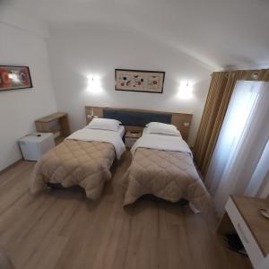 two beds in a room with wooden floors at Hotel Darda in Kamëz