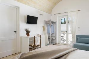 ein Schlafzimmer mit einem Bett und einem TV an der Wand in der Unterkunft Masseria Abadia Uno in Ostuni