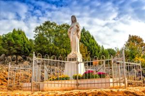 a statue of a woman standing in a park at Pansion Raspudić in Međugorje