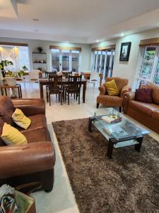 a living room with couches and a table and chairs at Jenvey House Selfcatering Apartments & BnB in Port Elizabeth