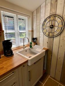 uma cozinha com um lavatório e um relógio na parede em The Leat at The Old Mill em Tavistock